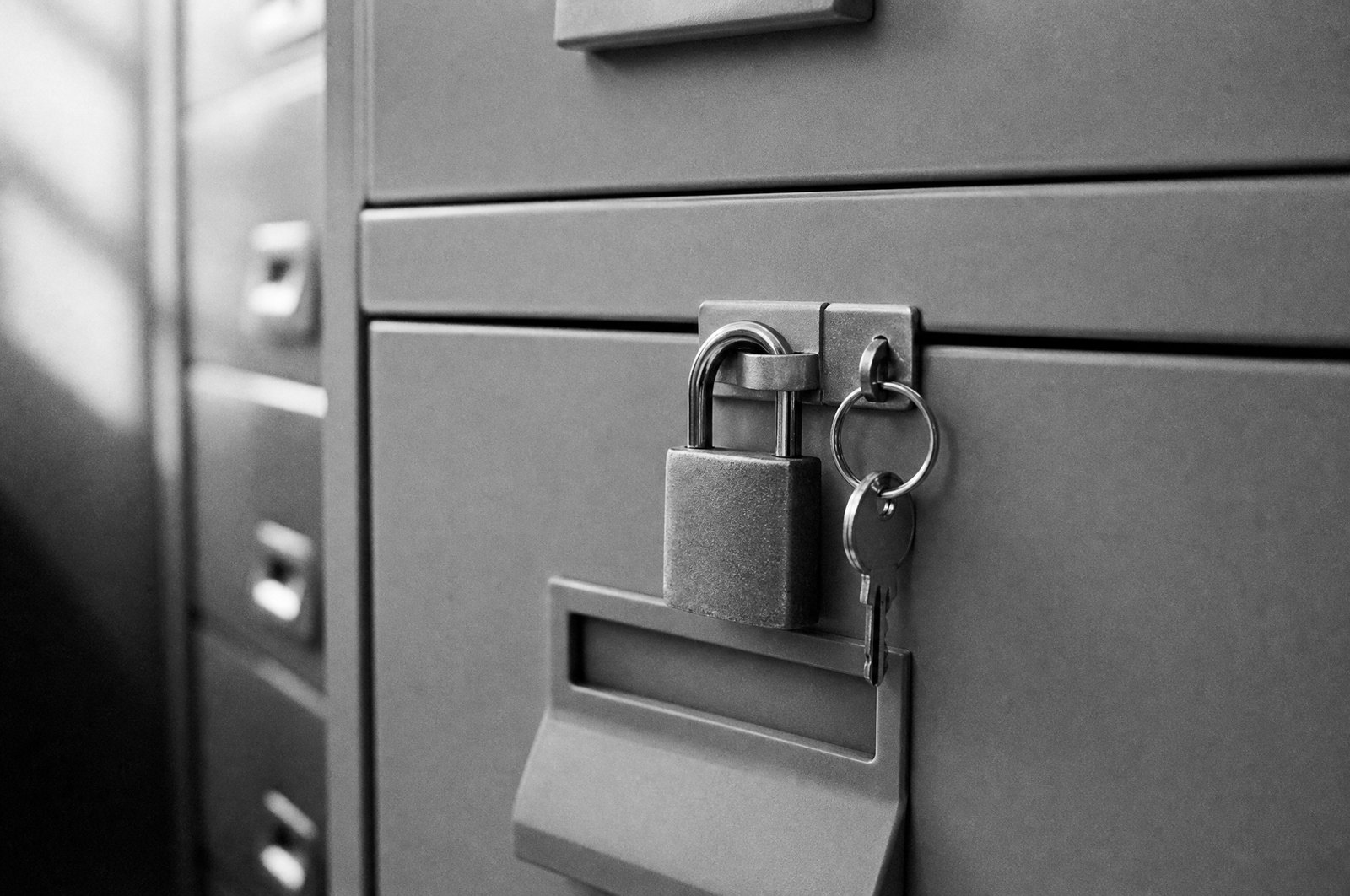 Metalowa szafa na dokumenty zamknięta na kłódkę z kluczami w zamku
